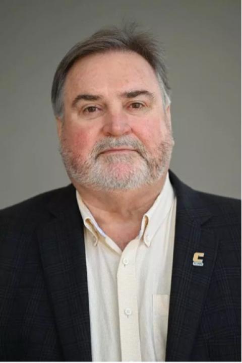Headshot of Scott Leroy in a dark suit and white button down shirt with a Power C alumni lapel pin on his left lapel.