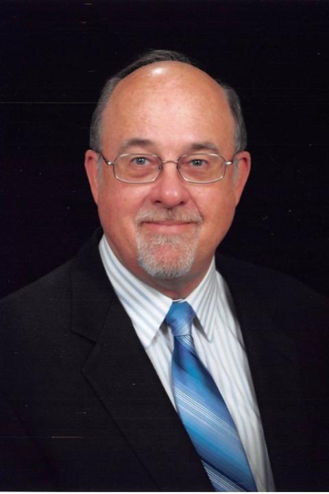 Headshot of Stephen Smith in a black suit, gray and white striped shirt, and blue tie.