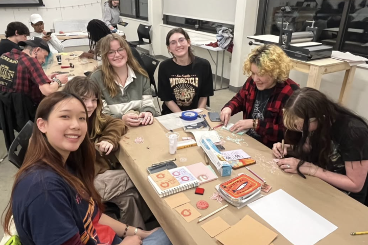 Students in The Art Collective sit together at a table making work.