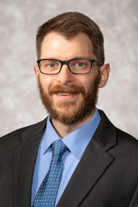 Brandon Bouchillon has short brown hair, a brown beard, and glasses. 