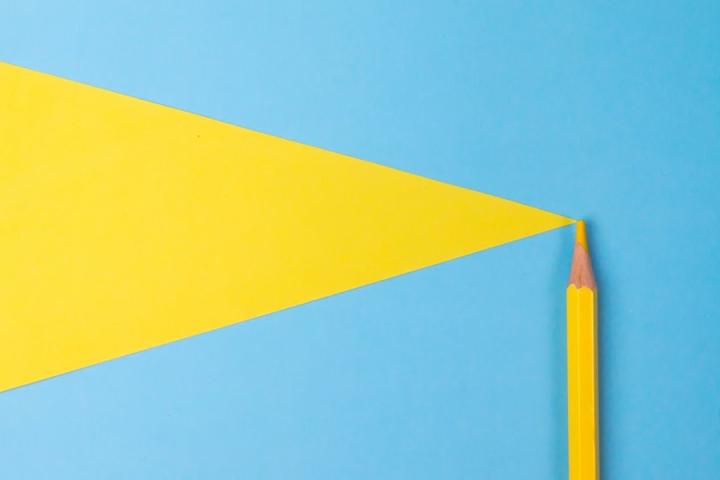 A yellow pencil drawing a yellow triangle on a blue background