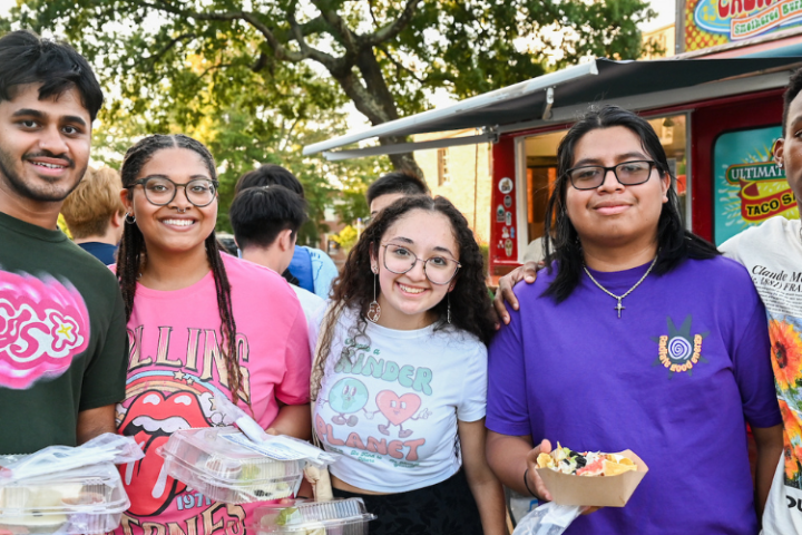 Five students holding food from food trucks at a campus event. 
