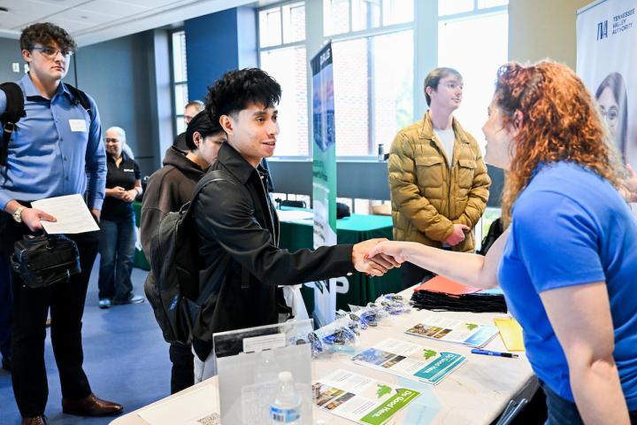 Student shaking hands with a company representative at a booth.