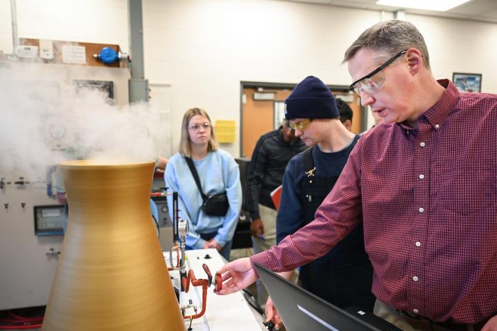 Students and a professor working with lab equipment that is purposefully creating smoke.