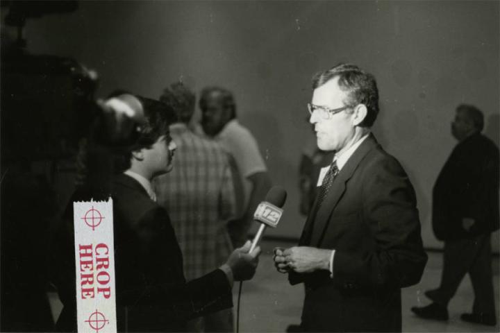 Black-and-white photograph of Fred Obear (right) being interviewed by an unidentified person (left) with a microphone. 