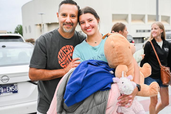 Father and Daughter holding bedding and stuffed animals at move in