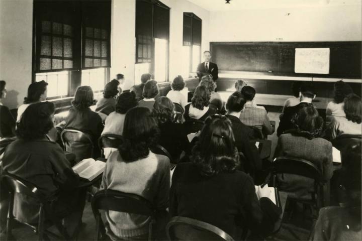 Black-and-white photograph of Frank Prescott giving a lecture to a room full of students. The captions on the reverse of the image read, "K-I", "Political Science; 194 307 1944", and "Frank Prescott."