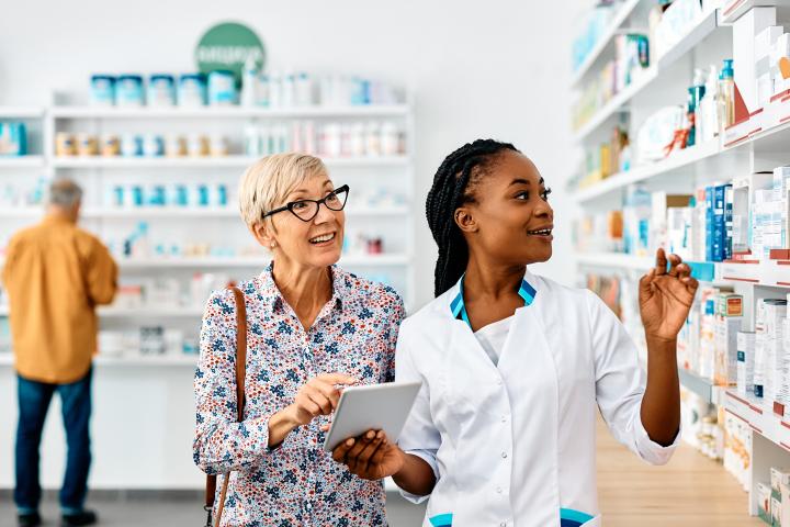 Female pharmacy tech helps an older woman to understand her prescription