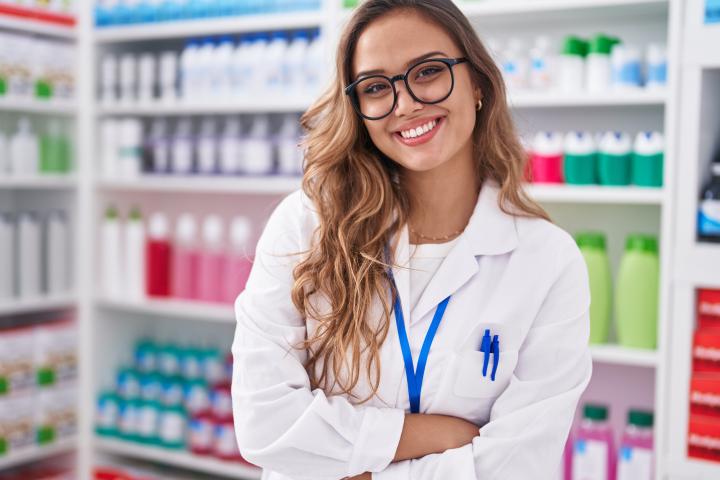 A female pharmacist smiles at her pharmacy