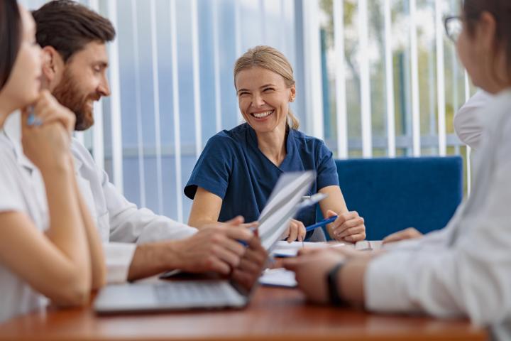 A female CMA smiles in a meeting with doctors