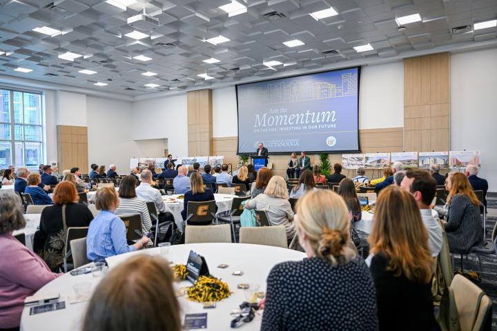 A crowd of people looking at a presenter at the Momentum Event