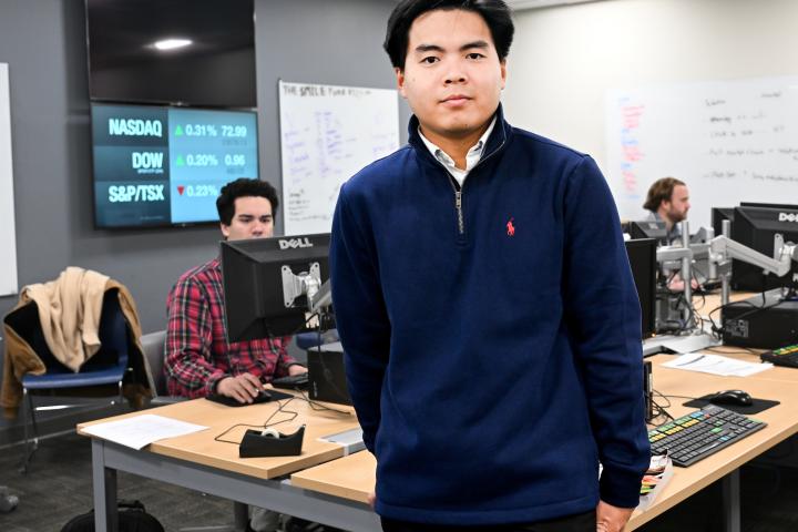 Vu Nguyen stand in the Bloomberg Lab with students on computers behind him. 