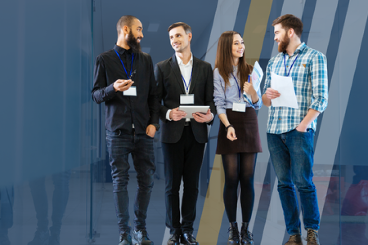 Four young professionals stand in a hallway discussing business. 