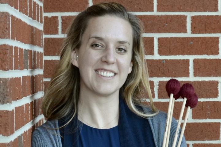 Woman holding mallets against brick wall.