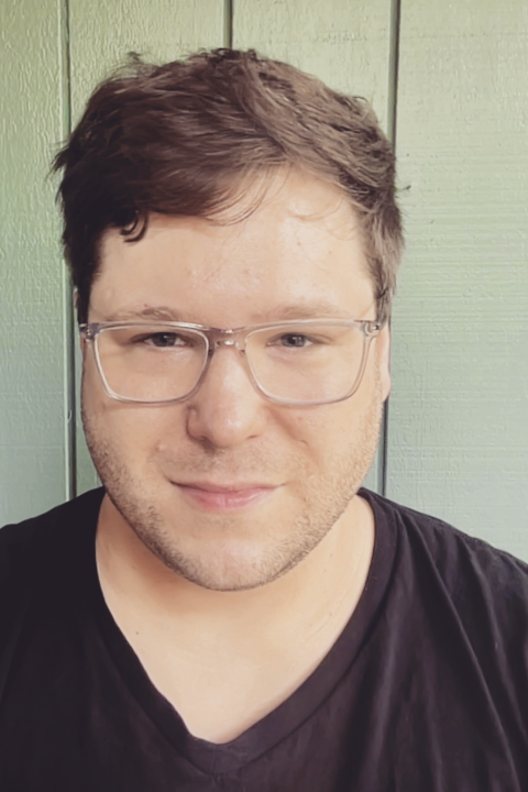 Dr. Justin Wymer wearing glasses and black t-shirt