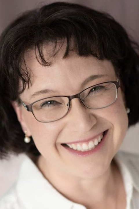 Woman with glasses smiling at camera for headshot