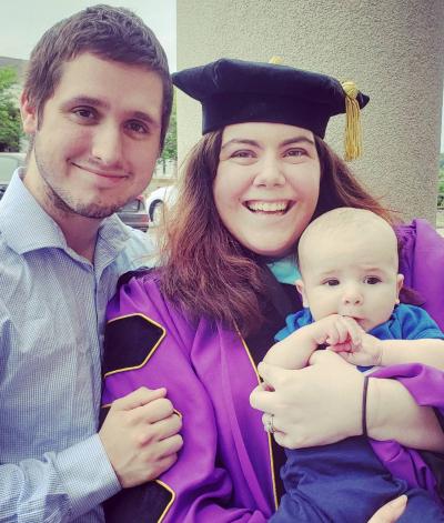 Allison Plattsmier in graduation attire beside partner with baby in hand