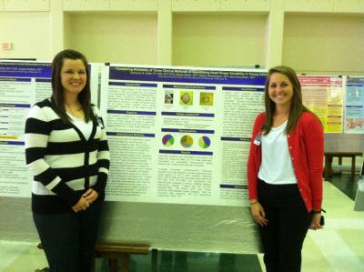 Two students stand by their research poster