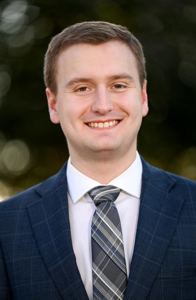 Profile image of Ryan Nichols wearing a blue plaid jacket a blue tie.