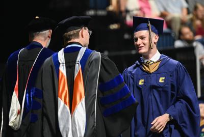 Grad student shaking hands as he walks across the stage
