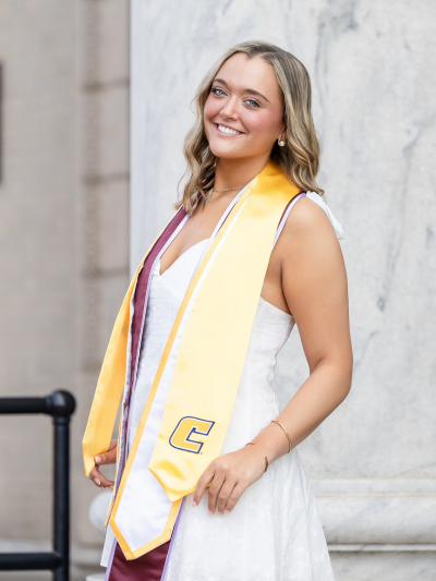 Ashlin posing while wearing her graduation stole and cords