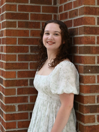 Emily standing and posing against a brick wall
