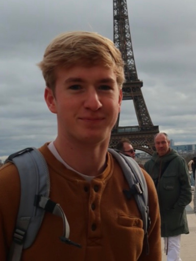 Jacob standing and posing in front of the Eiffel Tower. 