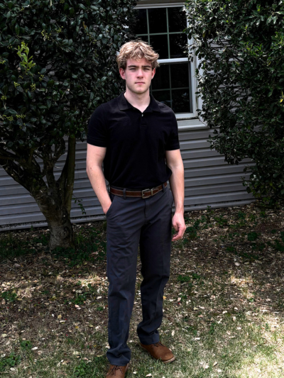 Tyson standing and posing in a yard with a window behind him. 