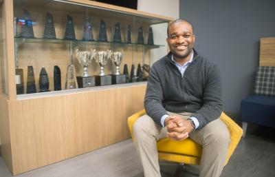 Ben Cheatham sits in Fletcher Hall in front of a trophy case.