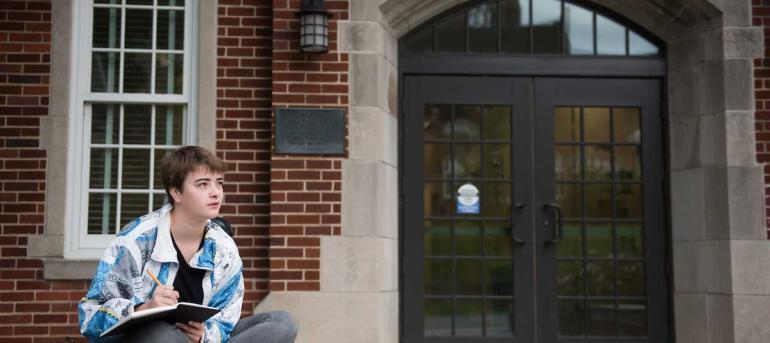 female student sitting in front of building