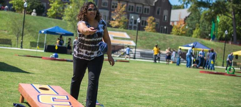 Founders Week Header Student tossing bean bag on chamberlain feild