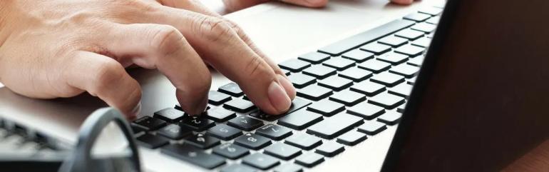 One singular hand on a laptop keyboard
