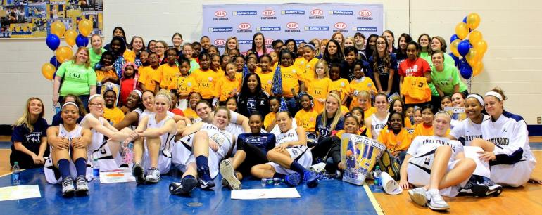 Play Believe Achieve Girls and Women in Sports group of women UTC students wearing basketball uniforms posing for a photo