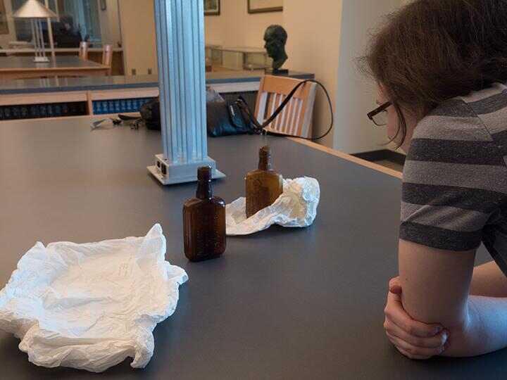 person looking glass containers on table in Special Collections