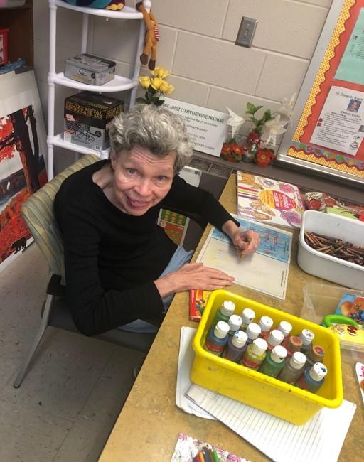 Woman sits at a table doing crafts