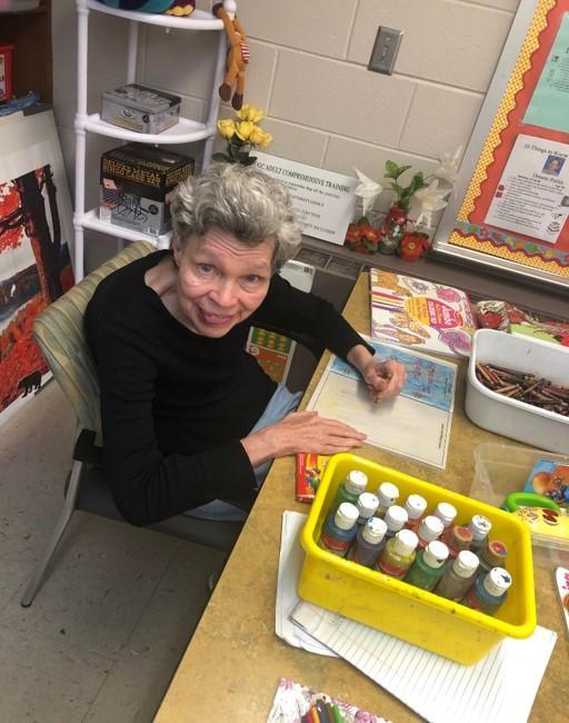 Woman sits at a table doing crafts