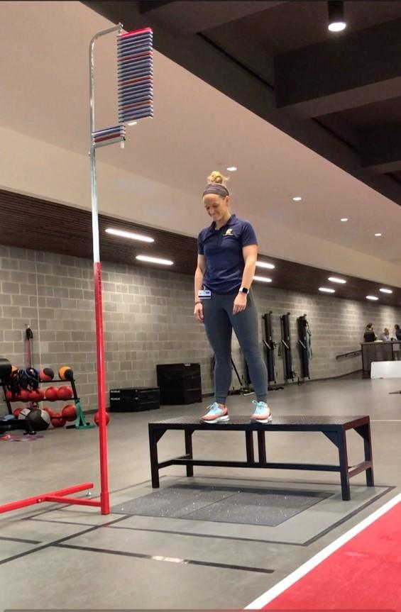 Woman stands on bench in gym