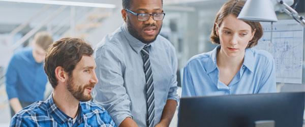 Three workers around a computer