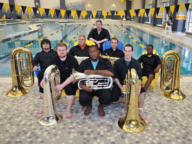 Tuba players take a group photo in front of the UTC pool