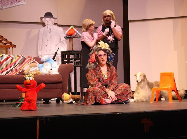 Performer sits on stage in a costume