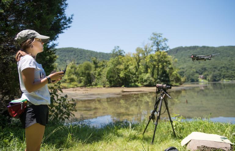 Environmental science grad student works on turtle research on Mullins Cove Road student works on turtle research near river with drone