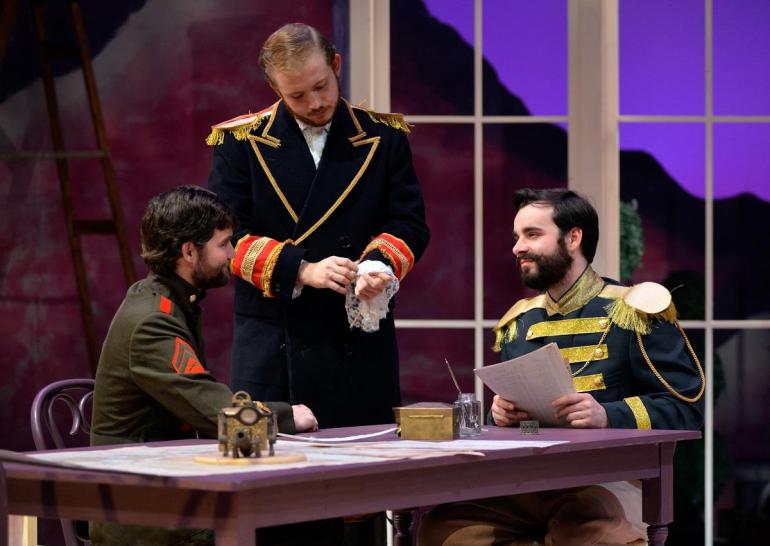 male cast members gather around a desk dressed in militarly-looking uniforms