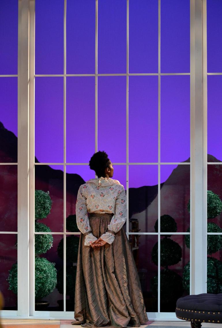 Cast member stands in front of large "window"