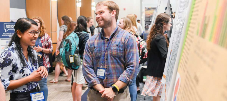 two students talk in front of poster at Research Dialogues