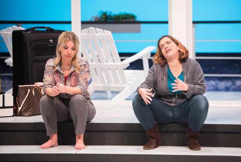 female cast members sit on steps on stage