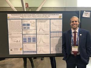 Student stands in front of poster presentation