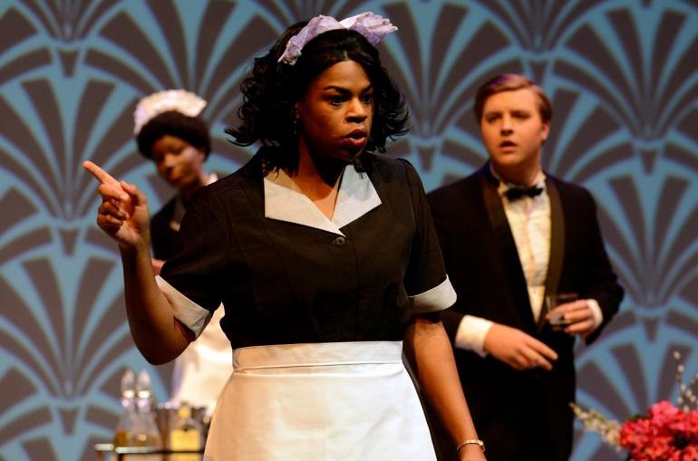 cast member on stage points finger with other cast members look at her