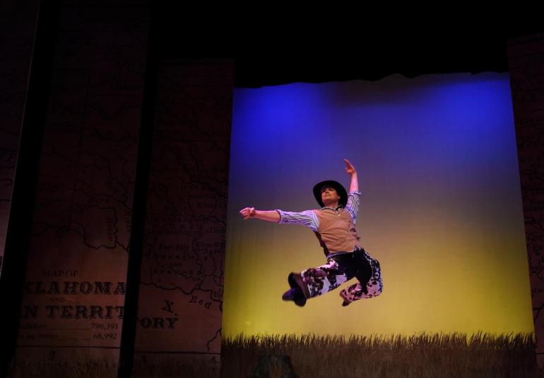 Male cast member dressed as cowboy jumps into air