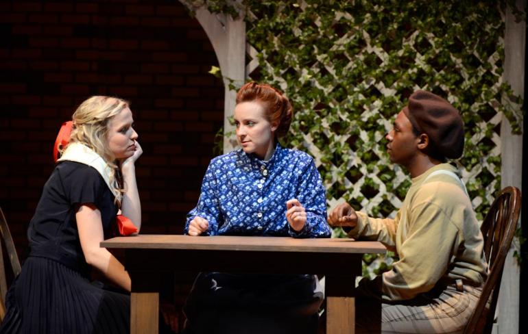 three female cast members sit at table