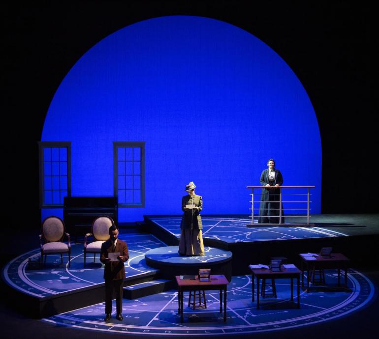 photo of entire stage with three cast members standing across it